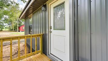 A wooden deck with a white door and a metal building.