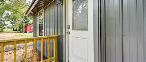 A wooden deck with a white door and a metal building.