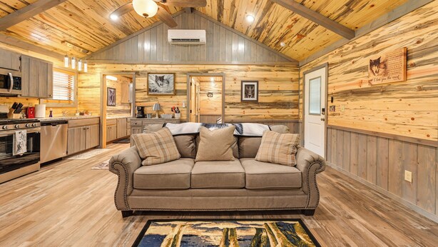 Acogedor interior de cabaña con techo de madera, un sofá, una cocina y un comedor.