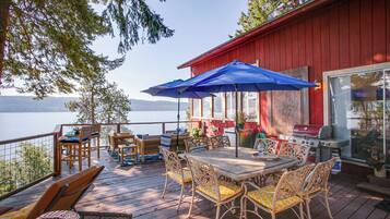 A deck with outdoor furniture, a barbecue grill, and a view of the lake.