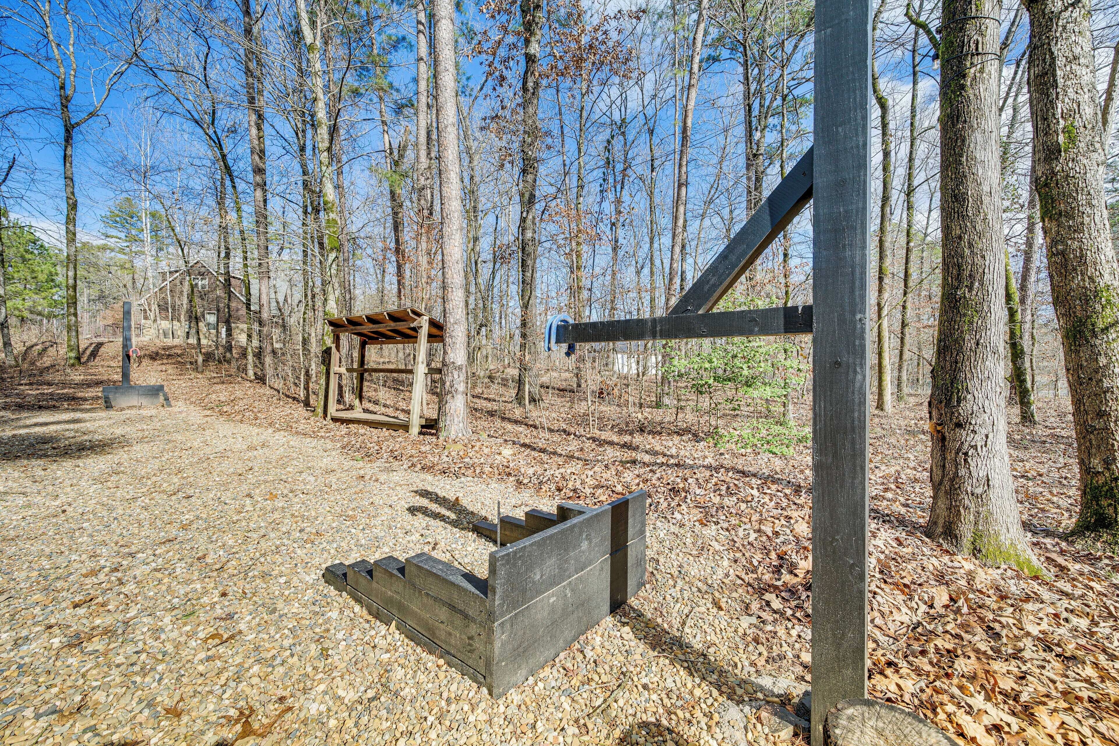 A rustic wooden structure in a forested area with a gravel path leading to it.