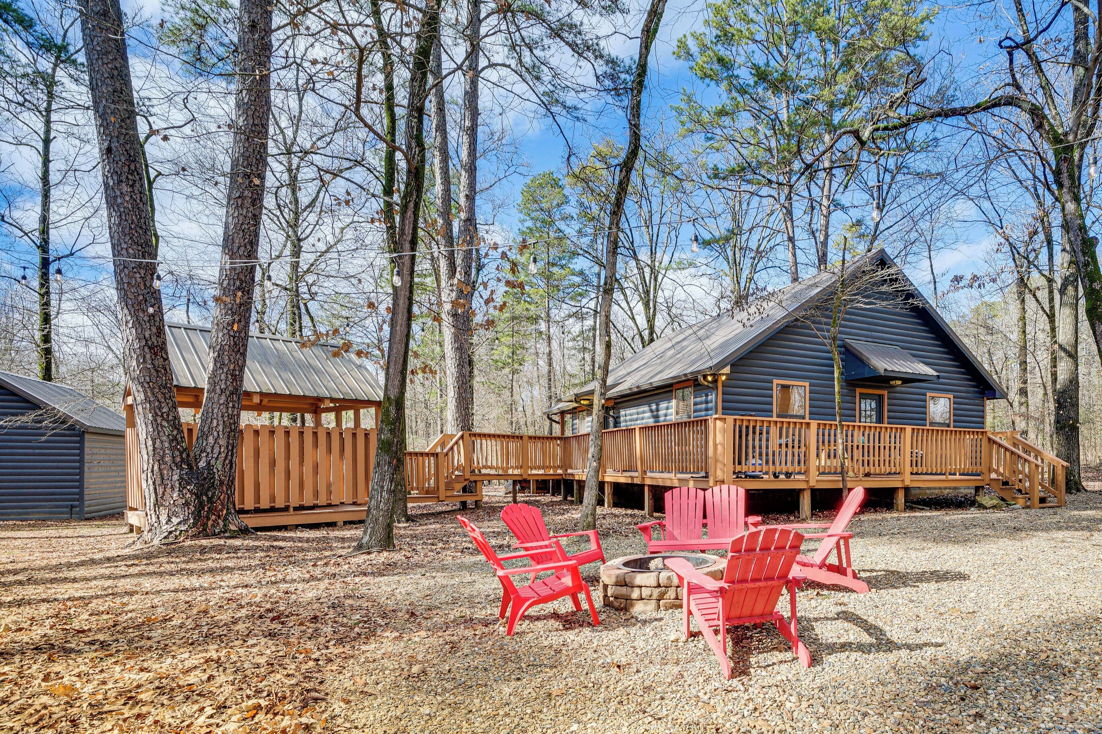 A cabin with a deck, surrounded by trees, and featuring outdoor seating.