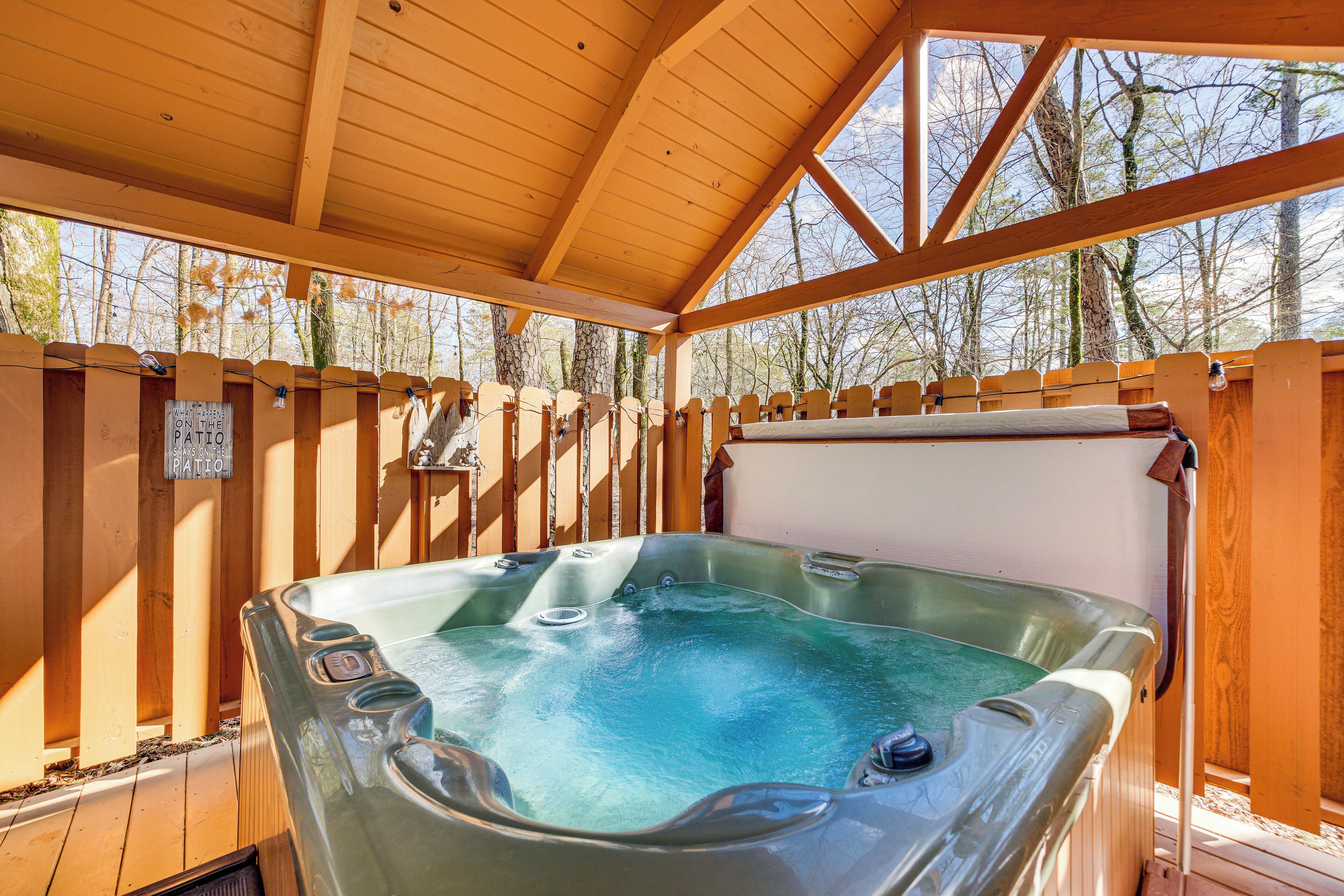 A hot tub in a wooden deck area with a view of trees.