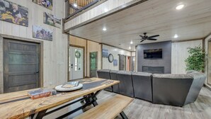 A modern living room with a wooden dining table, grey sofa, and a ceiling fan. - Family-friendly Broken Bow Home w/ Deck & Grill! (Broken Bow)