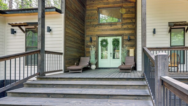 A wooden cabin with a porch, steps leading to the entrance, and two wicker chairs. - Family-friendly Broken Bow Home w/ Deck & Grill! (Broken Bow)