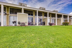 A motel with a covered outdoor seating area, multiple windows, and a well-maintained lawn.