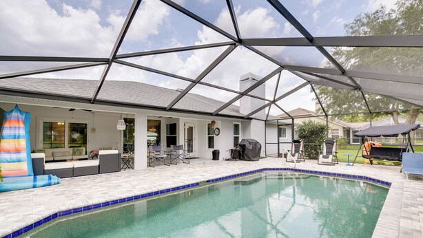 Une piscine avec un patio couvert, un espace salon extérieur et un barbecue.