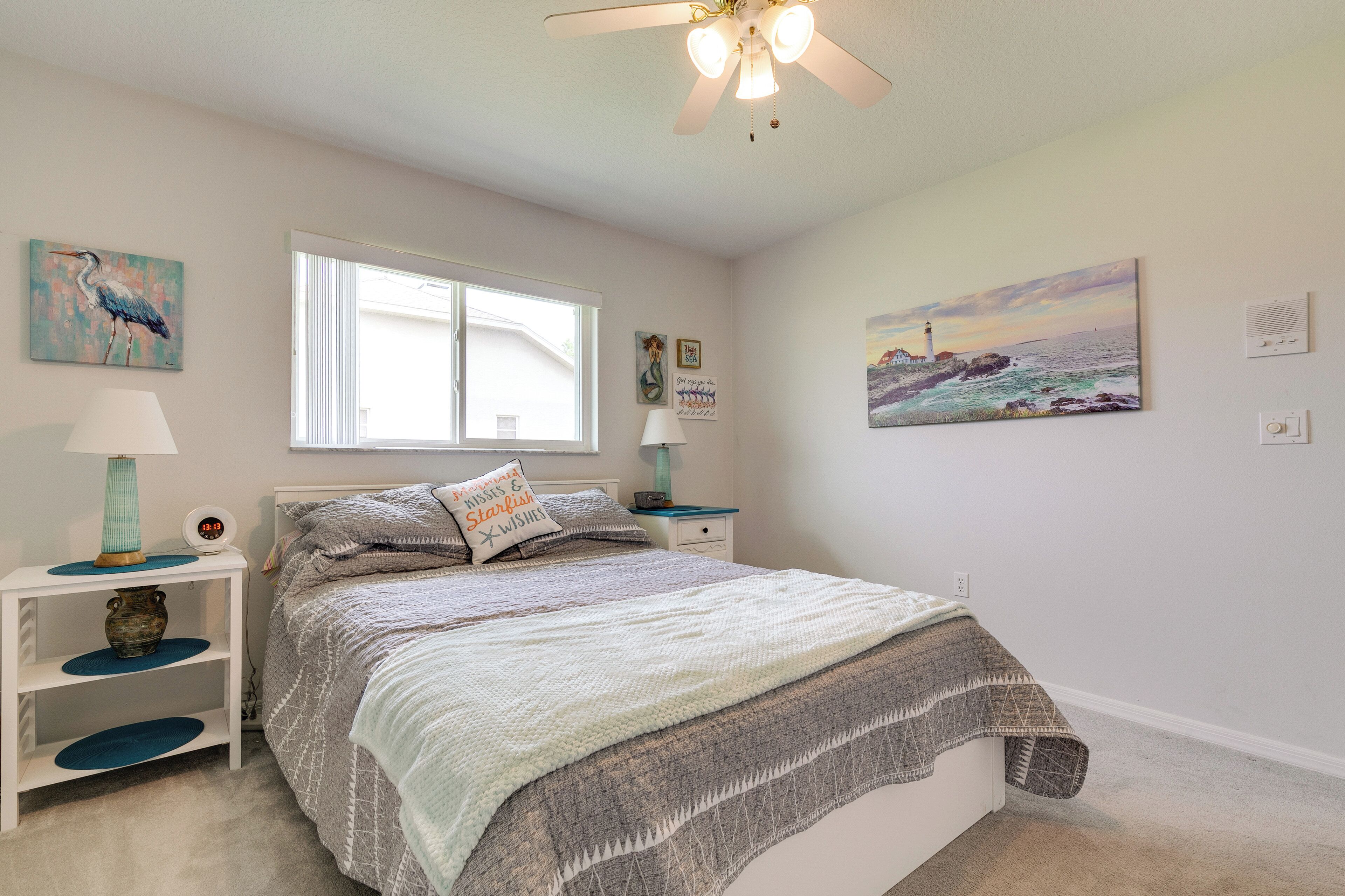 A bedroom with a bed, a nightstand, a window, and wall art.