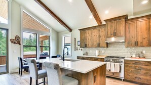 A modern kitchen with a large island, wooden cabinets, and a view of the outdoors. - Government Camp Vacation Rental w/ Private Hot Tub (Government Camp)