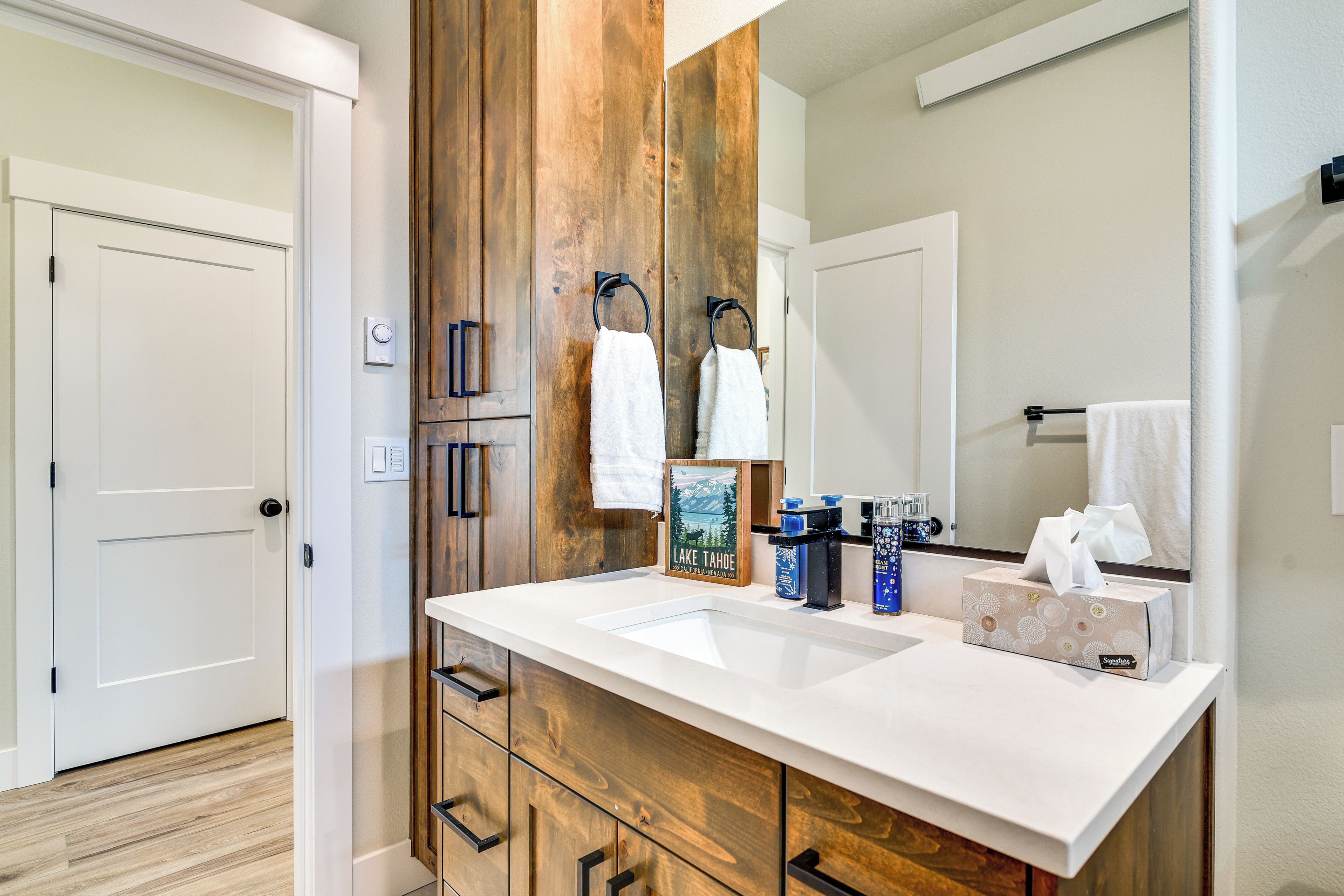 A bathroom with a wooden vanity, a large mirror, and a white sink.
