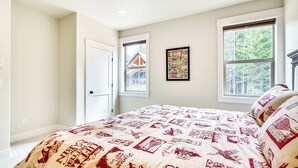 A bedroom with a bed, two windows, a door, and a wall-mounted poster. - Government Camp Vacation Rental w/ Private Hot Tub (Government Camp)
