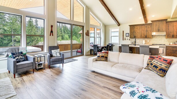 A spacious living area with a large white sofa, two armchairs, and a coffee table. There are large windows offering a view of the outdoors. - Government Camp Vacation Rental w/ Private Hot Tub (Government Camp)