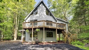 A cabin with a balcony, a porch, and a staircase.