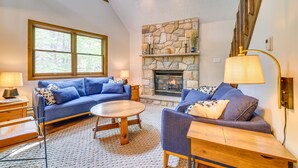 A cozy living room with a stone fireplace, two sofas, a coffee table, and a lamp.