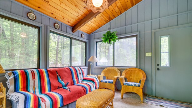 A cozy room with a striped sofa, wicker chairs, and a hanging plant.