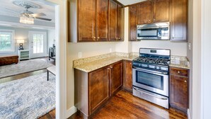 A kitchen with wooden cabinets, a stainless steel stove, and granite countertops. - Pet-friendly Home w/ Yard, Near Downtown Royal Oak (Royal Oak)