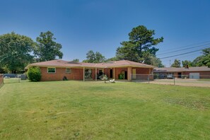 A single-story brick house with a covered porch, a fenced yard, and a garage.