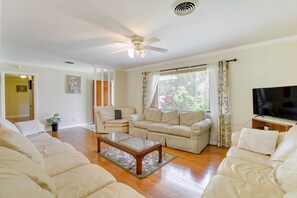 A living room with a ceiling fan, a television, and a large window with curtains. - Cozy Home in Montgomery ~ 3 Mi to ASU Campus! (Montgomery)