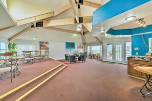 A spacious room with a high ceiling, wooden beams, a large window, a dining area with chairs, and a kitchen counter. - Kissimmee Vacation Rental - 5 Mi to Disney World! (Kissimmee)