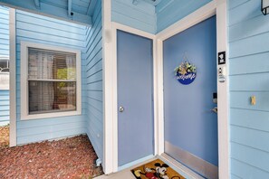 A house with a blue exterior, a front door with a 'welcome' sign, a window with blinds, and a doormat with Mickey Mouse. - Kissimmee Vacation Rental - 5 Mi to Disney World! (Kissimmee)