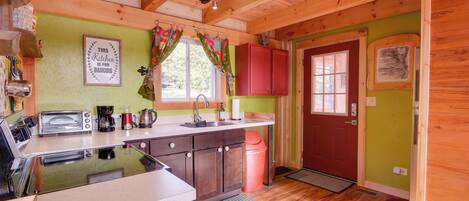 A kitchen with wooden beams, a toaster, a sink, and a red door.