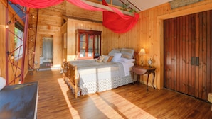 Camera da letto in una baita di legno, con un letto, un comodino e una tenda rossa.