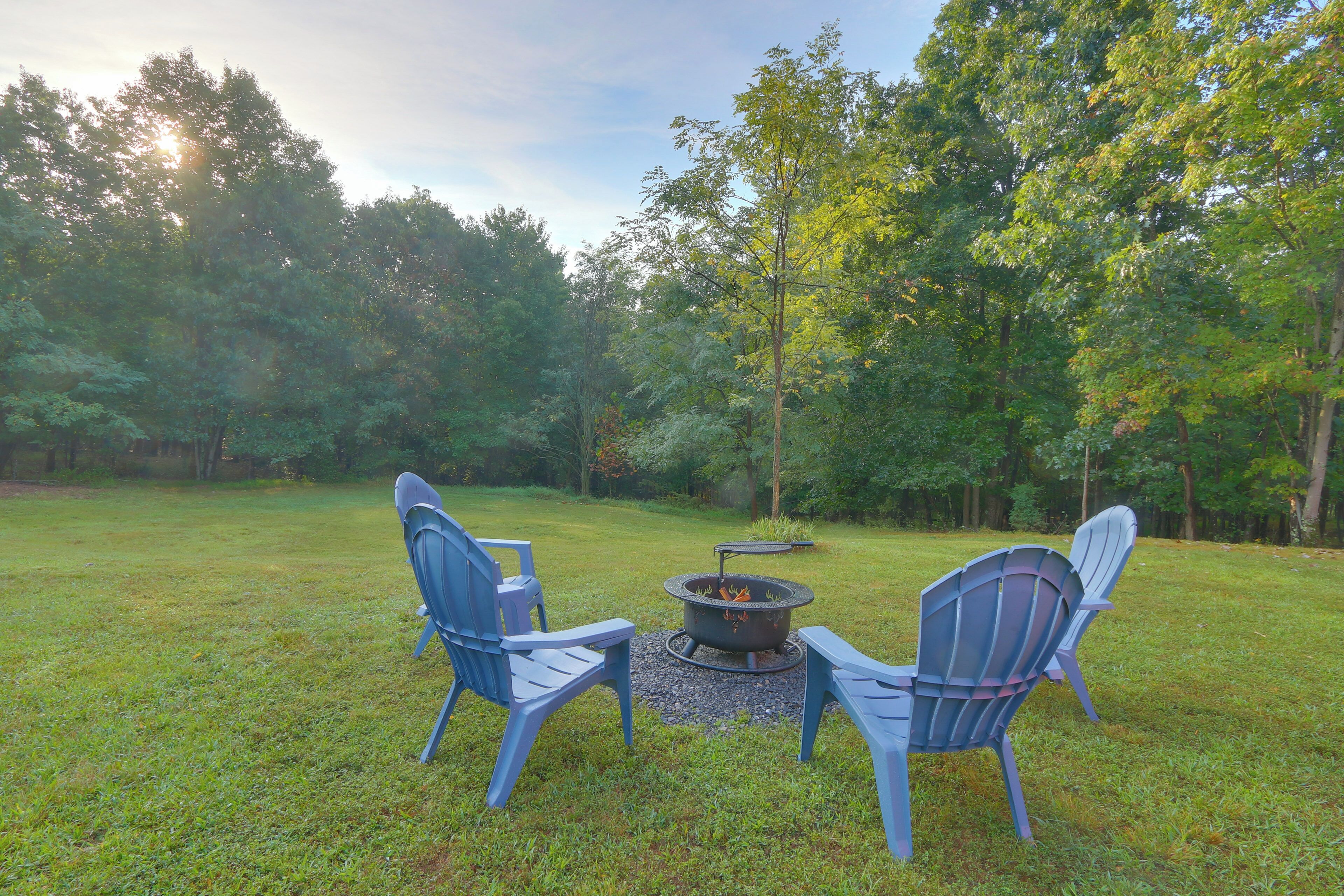 A grassy outdoor area with two Adirondack chairs facing a fire pit.