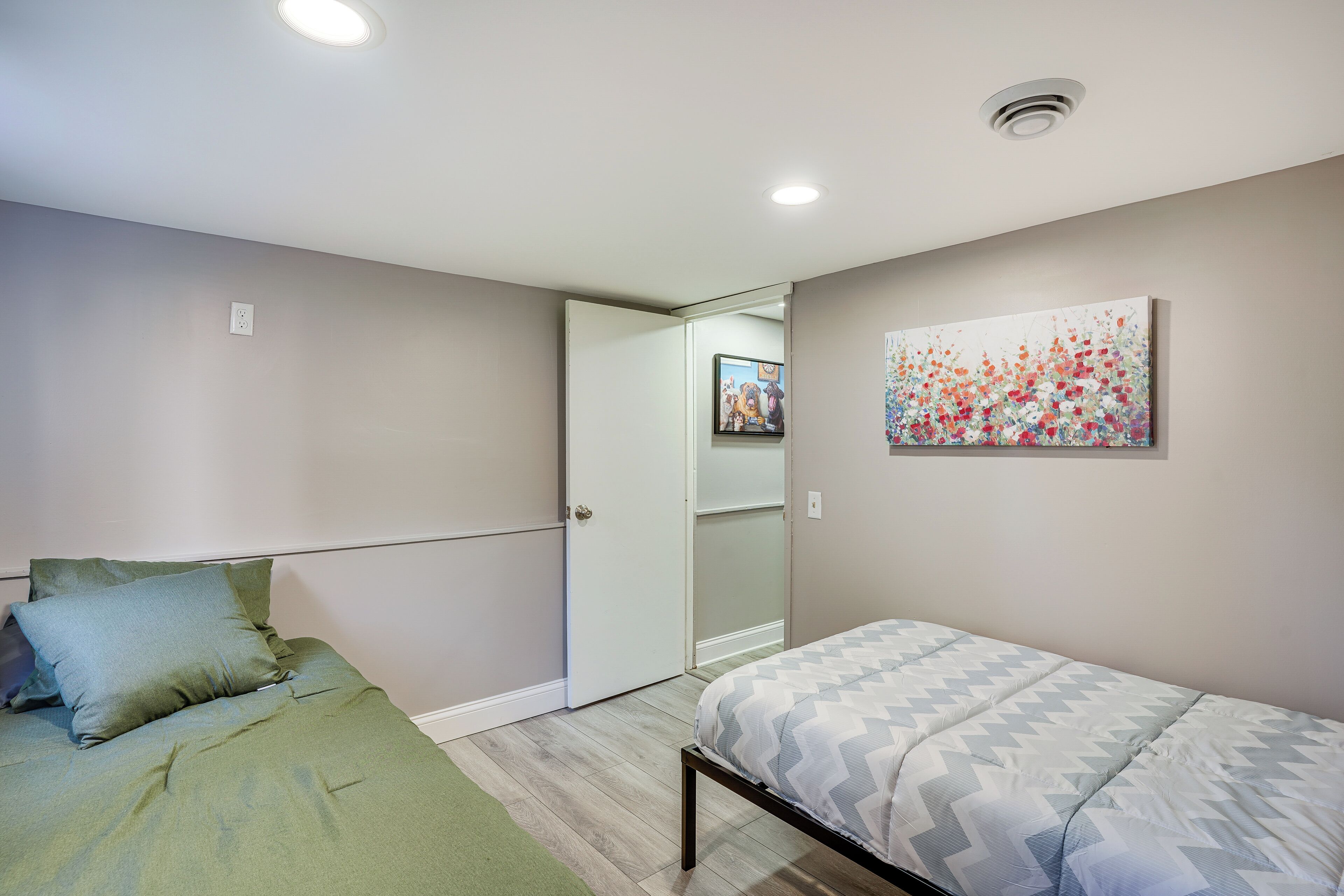 Ein Schlafzimmer mit einem Bett, einem Nachttisch, einem an der Wand montierten Fernseher und einer Tür zu einem anderen Raum.