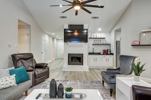 A modern living room with a fireplace, leather recliner, and a dining area with a white table and chairs.