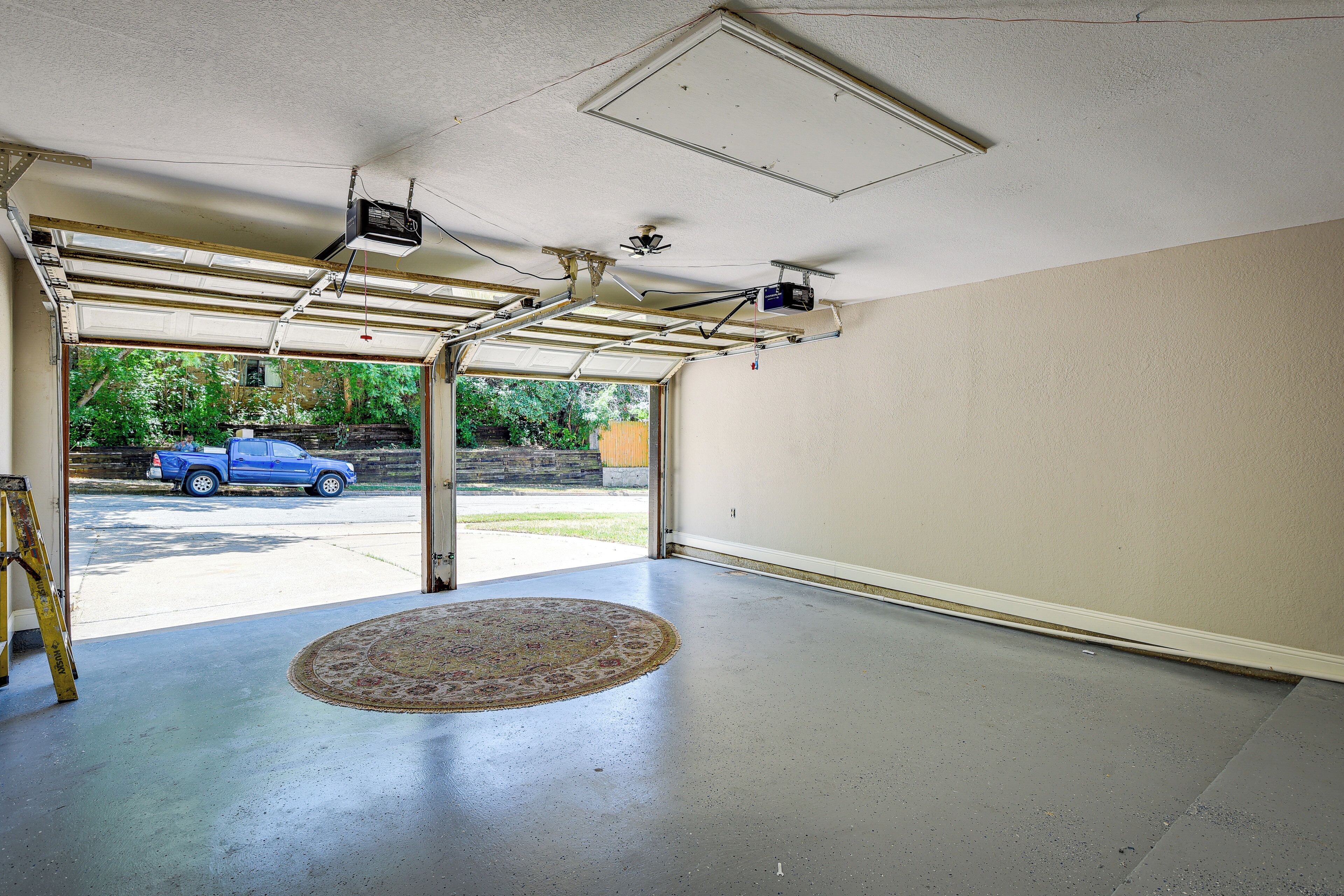 A garage with a large open door, a ceiling fan, and a projector mounted on the ceiling.