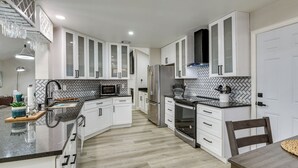 A modern kitchen with white cabinets, a stainless steel refrigerator, and a herringbone-patterned backsplash. - 11 Mi to Six Flags! Poolside Oasis in Bedford (Bedford)