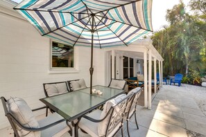 A patio with a glass table and chairs, a striped umbrella, and a covered seating area with blue chairs. - Osprey Vacation Rental w/ Kayaks: 4 Mi to Beach! (Osprey)