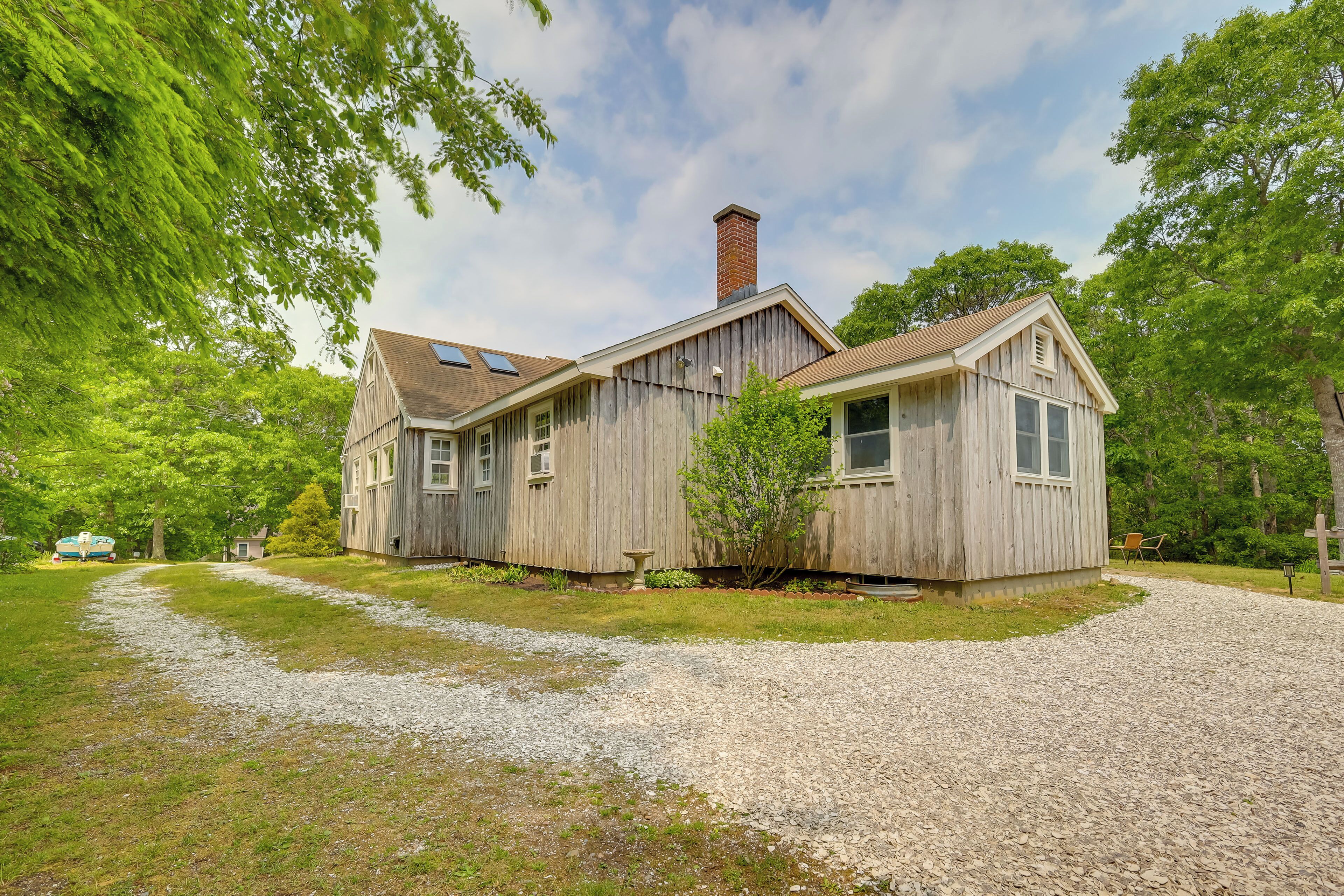 A rustic wooden house with a gravel driveway and a small garden area.