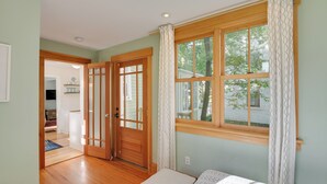 Une pièce avec une porte en bois, une fenêtre avec des rideaux, un lit et une vue sur l’extérieur.