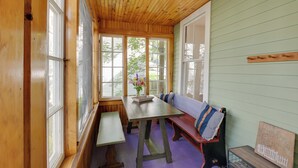 Un intérieur en bois avec un banc, une table et une fenêtre donnant sur un paysage verdoyant.