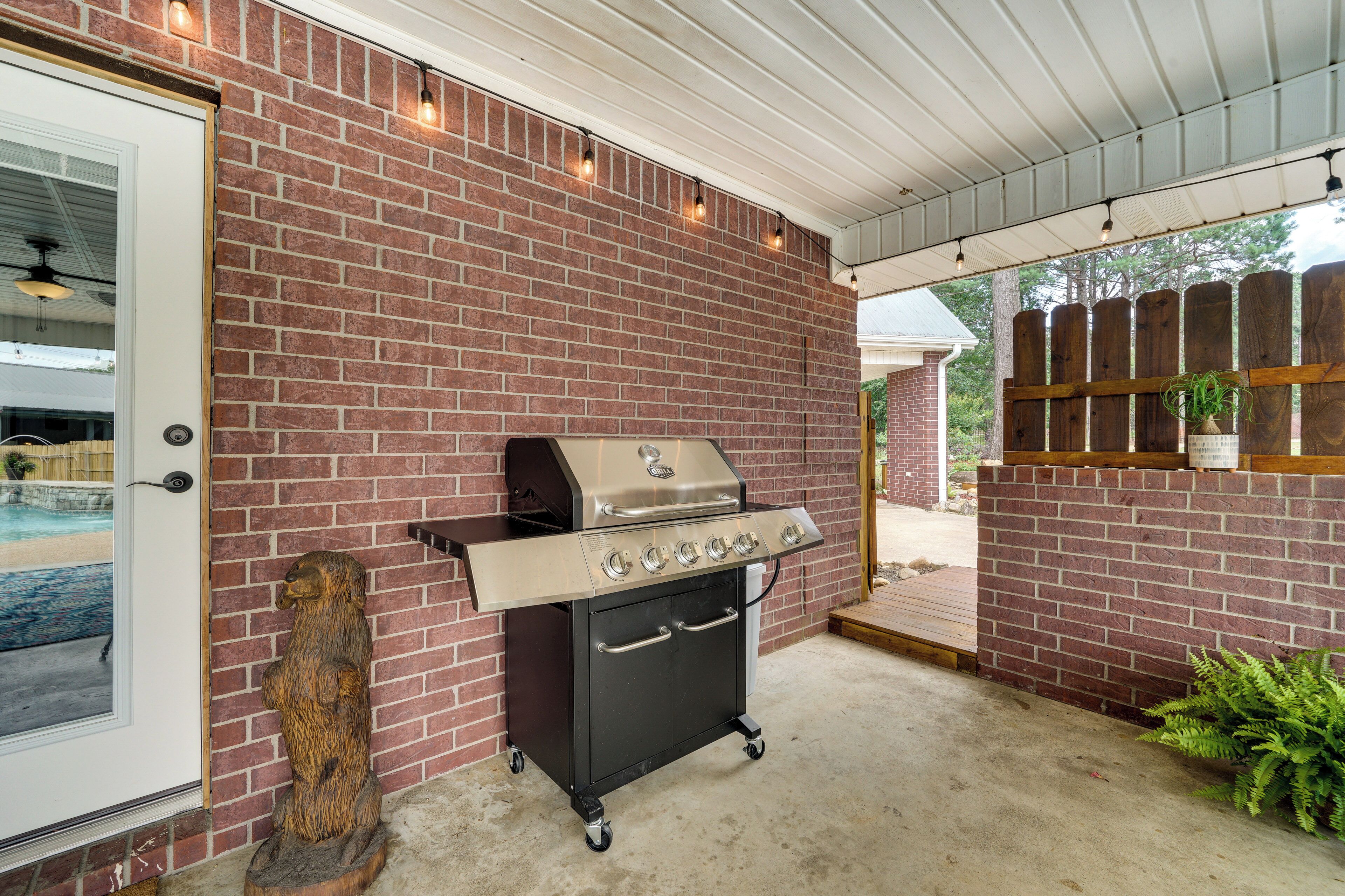 Ein Grill aus Ziegelsteinen mit Schornstein, eine Holzschnitzerei eines Bären und ein Blumentopf.