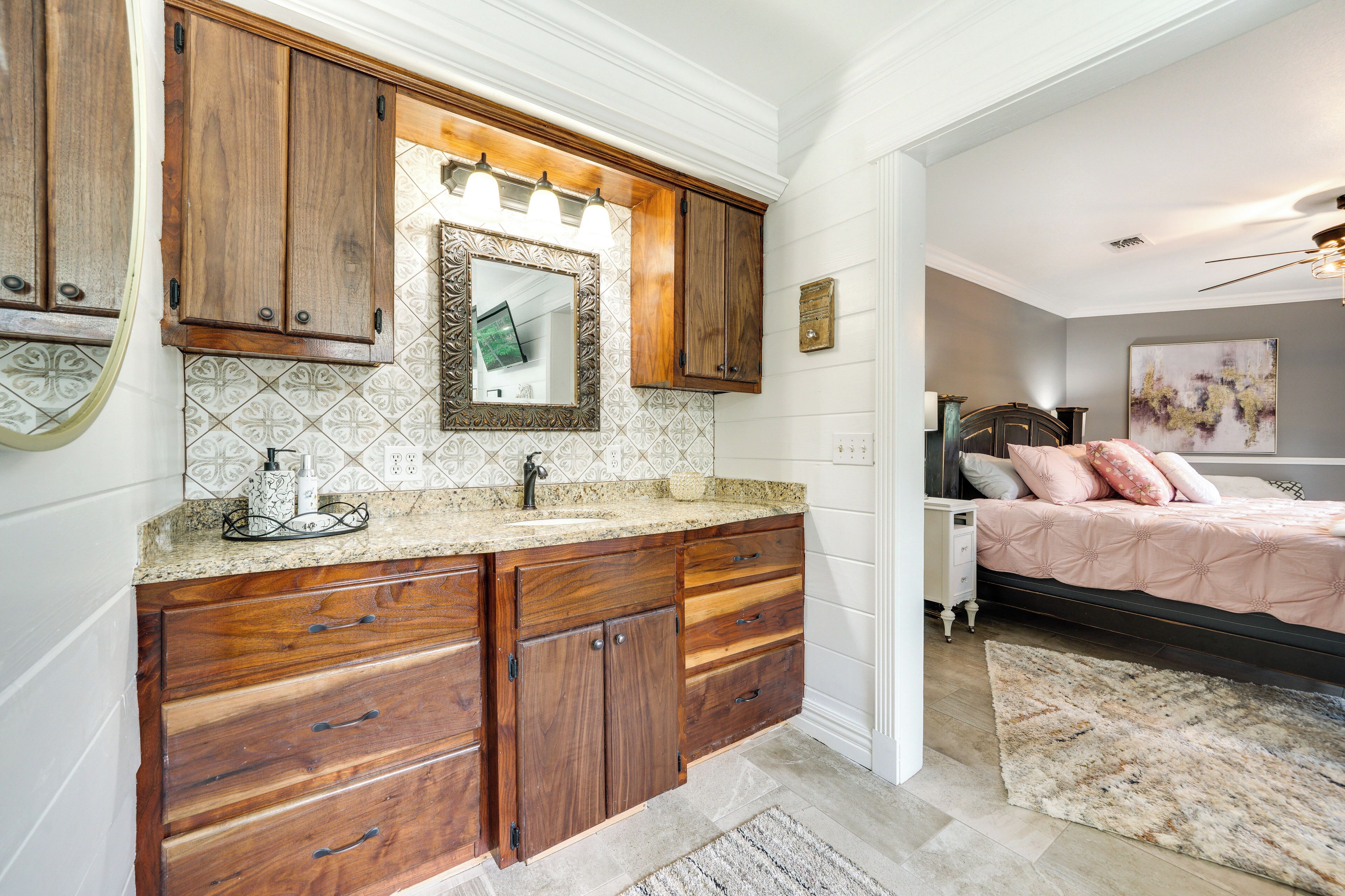 Un baño con armarios de madera, un lavabo y un espejo.