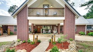 A two-story brick building with a balcony, a front porch, and a pathway leading to the entrance. - Broken Bow Vacation Rental w/ Pool & Hot Tub! (Broken Bow)