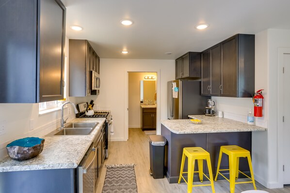 A modern kitchen with dark cabinets, a granite countertop, a stainless steel sink, and a built-in stove. - Dolores Townhome w/ Mountain Views: Near River! (Dolores)