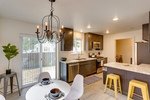 A modern kitchen with a central island, stainless steel appliances, and a dining area with white chairs and a table. - Dolores Townhome w/ Mountain Views: Near River! (Dolores)