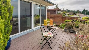 A deck with two folding tables and chairs, a wooden fence, and a view of the neighborhood. - Stunning Bay-view Home in Kensington! (Berkeley)