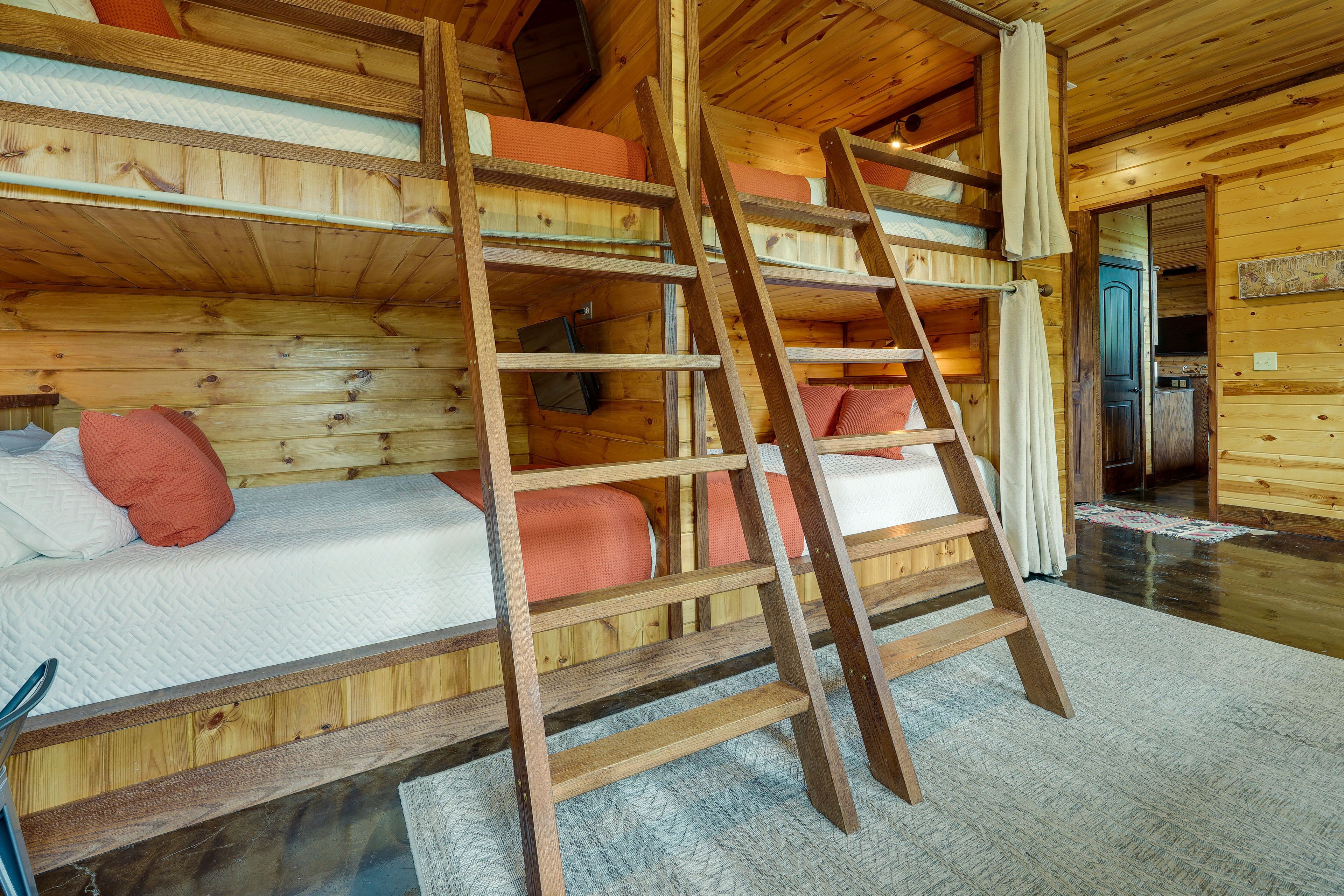 A wooden cabin with bunk beds, a ladder, and a visible kitchen area.