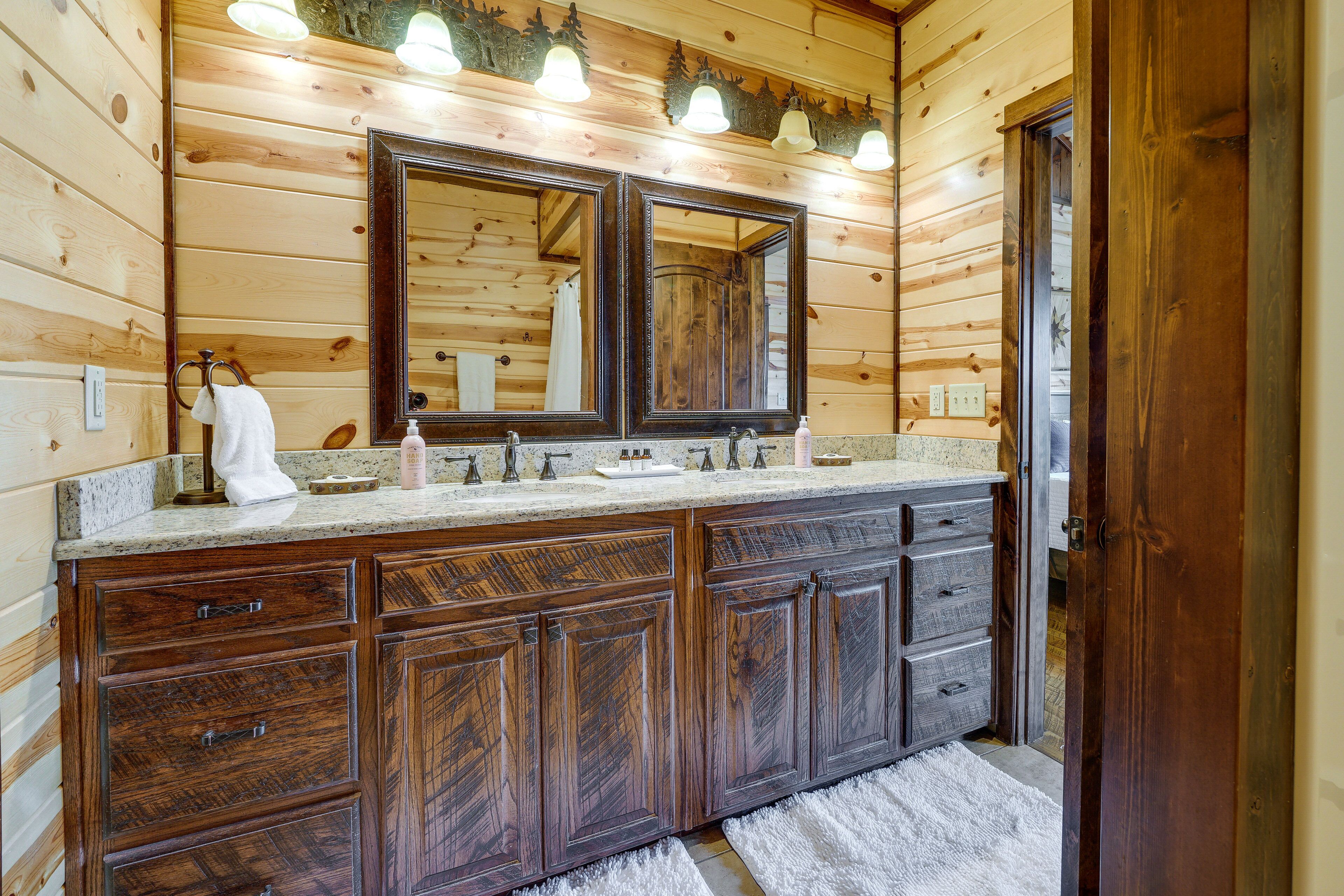 Ein Badezimmer in einer Holzhütte mit einem Doppelwaschbecken, großen Spiegeln und einem Holzkabinett.