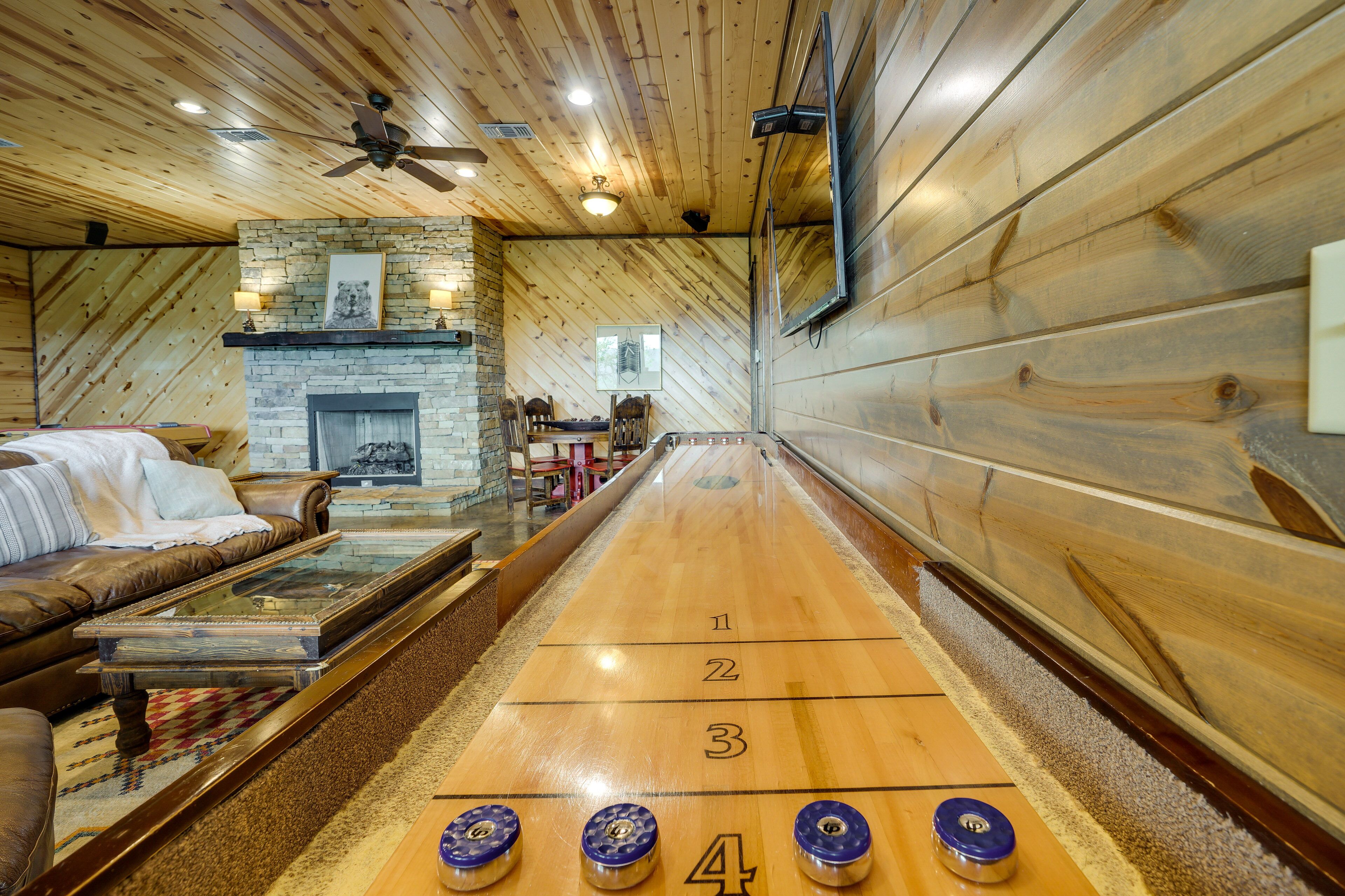 Un intérieur en bois avec une table de jeu de palet, une cheminée en pierre et un canapé en cuir.