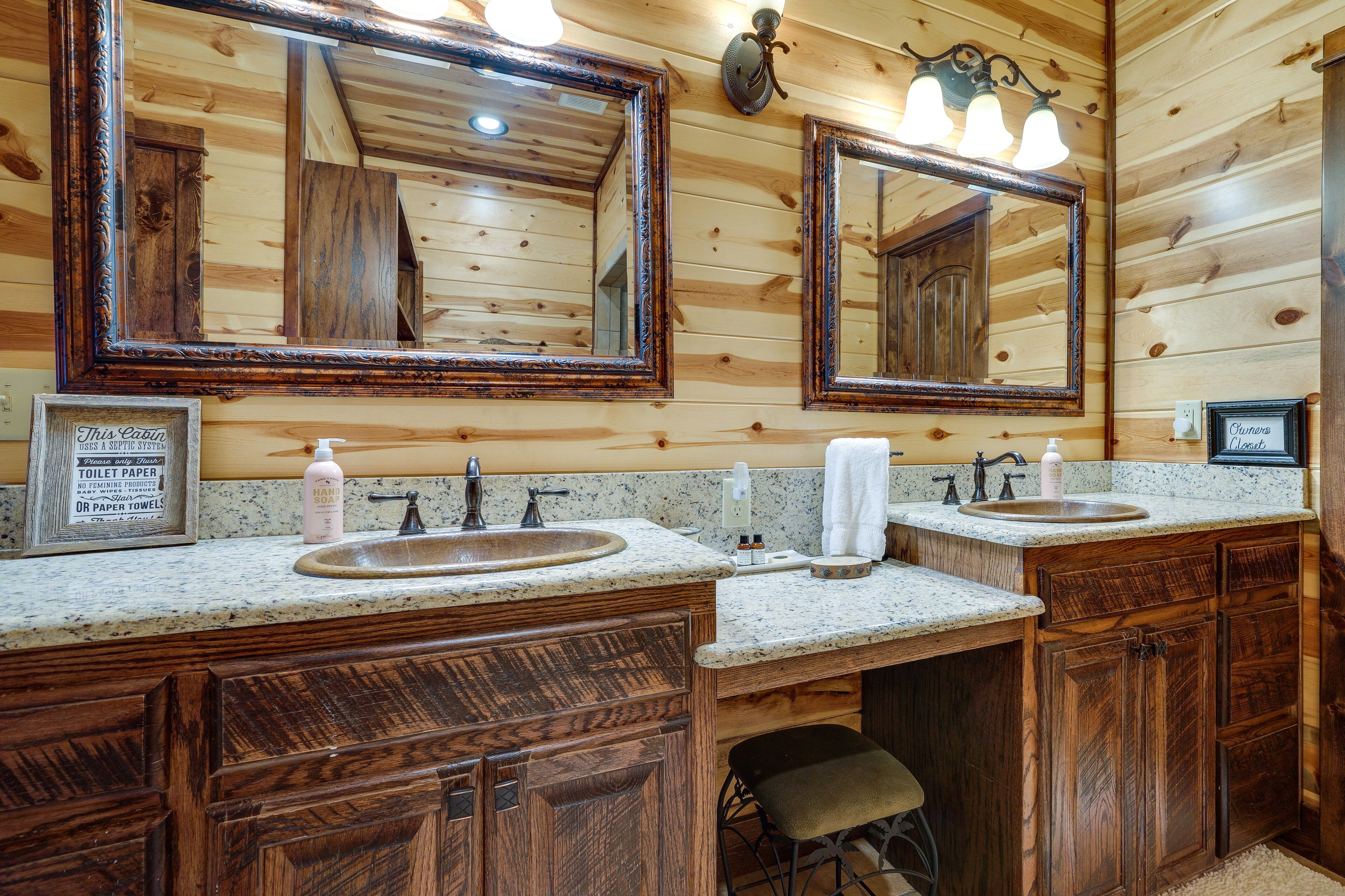 A wooden cabin bathroom with two sinks, wooden cabinets, and large mirrors.