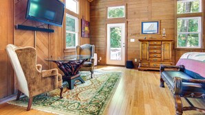Una habitación con paneles de madera, un televisor grande, un sofá, una silla, una mesa y un armario.