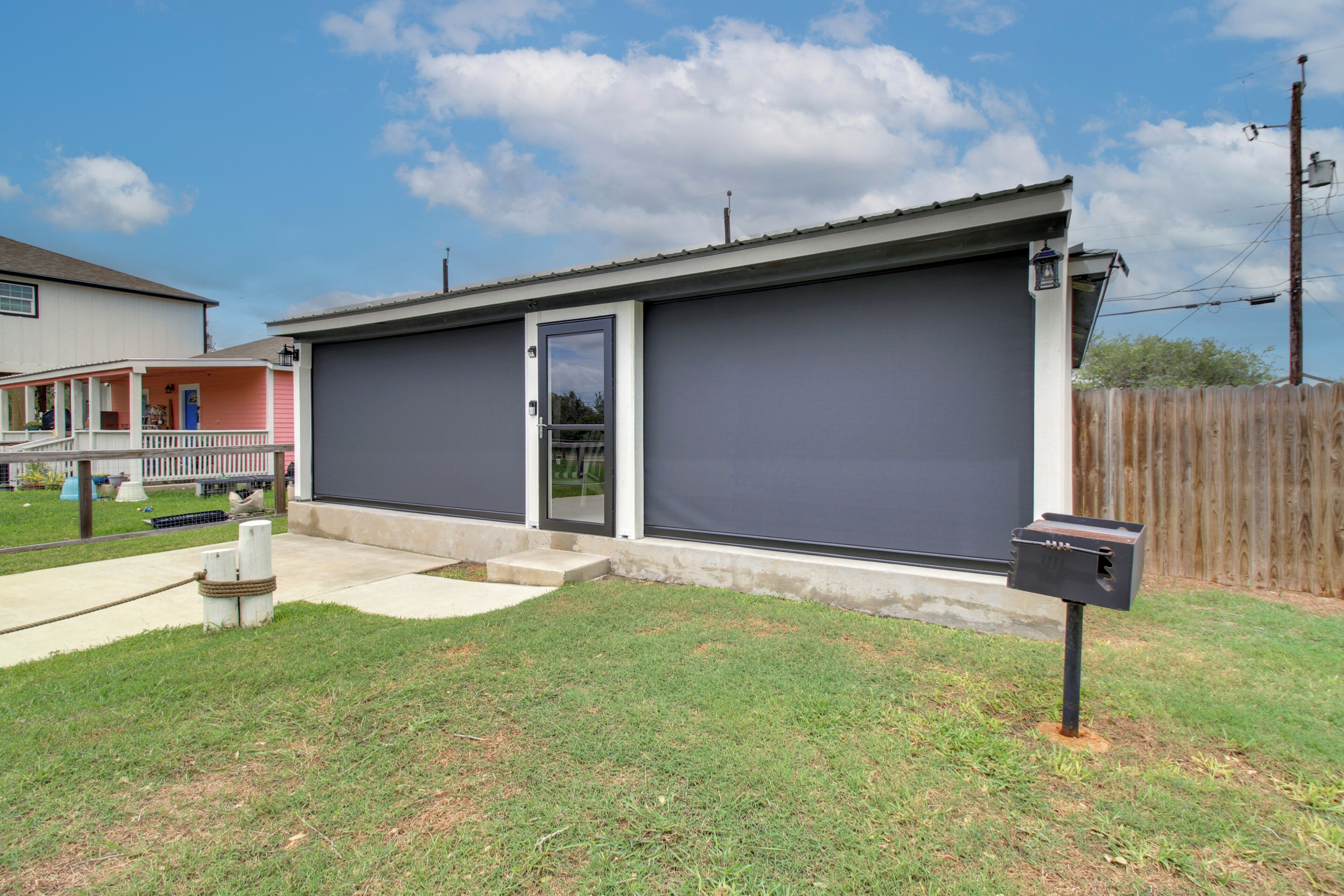 A residential garage with a sliding door, a mailbox, and a wooden fence in the background.