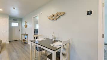 A dining area with a table set for two, a decorative wall piece, and a thermostat on the wall.