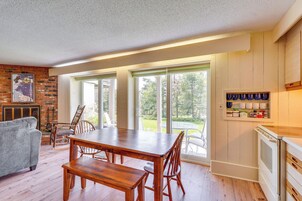 Un comedor con una mesa y sillas de madera, una chimenea y vistas al exterior a través de grandes puertas correderas de vidrio.