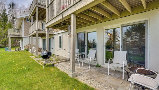 Een gebouw met twee verdiepingen, een overdekt terras, zitplaatsen buiten en een barbecue.